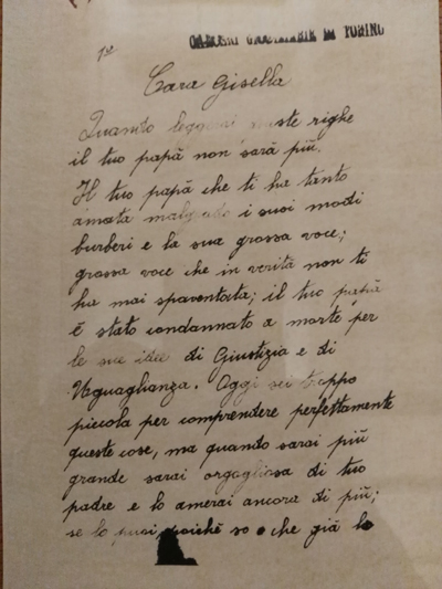 L’immagine riproduce la prima pagina della lettera di Giambone alla figlia Gisella. In alto a sinistra c'è il numero 1, mentre a destra è impresso il timbro delle carceri giudiziarie di Torino.
